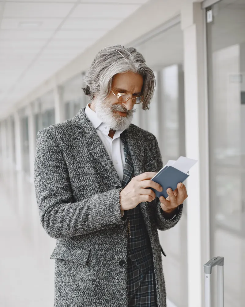 Homme aux cheveux gris qui vérifie son passeport dans un couloir d'aéroport